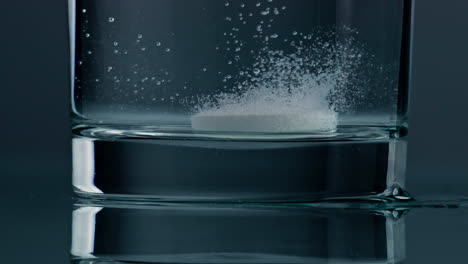 Effervescent-drug-falling-glass-bottom-closeup.-White-tablet-dissolving-in-water