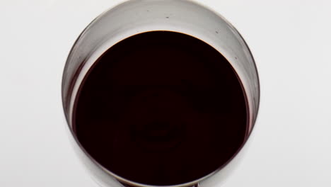 Red-wine-droplet-falling-rippling-in-goblet-closeup.-Smooth-beverage-surface