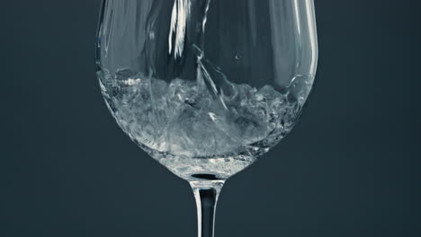 Sprudelndes-Wasser-Gießt-Glas-Auf-Dunklem-Hintergrund,-Nahaufnahme.-Luftblasen-Steigen-Auf