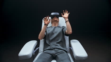 Haptic-sensors-hands-man-sitting-armchair-zoom-out.-Person-exploring-cyberspace