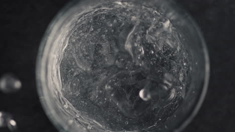 Hands-throw-ice-cube-into-glass-with-water-closeup.-Making-cocktail-concept