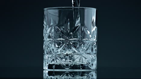 Kristallklares-Wasser-Aus-Einem-Glas-Auf-Dunklem-Hintergrund,-Nahaufnahme.-Frische-Flüssigkeit-Spritzt
