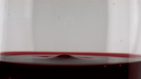 Rotwein-Tropft-Aus-Einem-Glas,-Nahaufnahme.-Glatte,-Kreisförmige-Oberfläche-Der-Flüssigkeit-Aus-Trauben