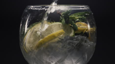Jet-water-filling-lemon-mint-wineglass-closeup.-Preparing-homemade-drink-concept