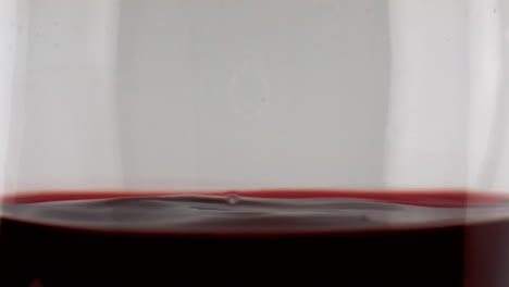 Closeup-wine-droplets-rippling-splashing-in-goblet.-Merlot-red-beverage-waving