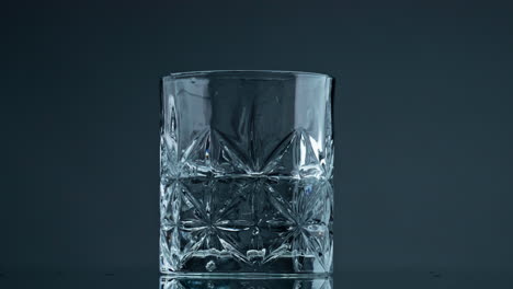 Winkendes-Flüssiges-Wasserglas-Auf-Dunklem-Hintergrund,-Nahaufnahme.-Mineralflüssigkeit-Spritzt