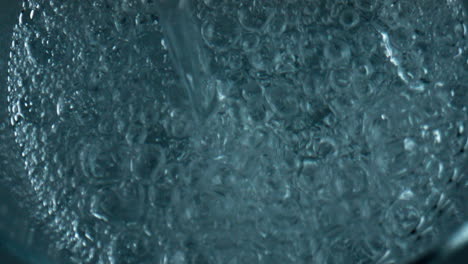 Bubbling-water-pouring-glass-top-view.-Closeup-air-bubbles-rising-exploding