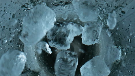 Ice-cubes-falling-blender-closeup.-Grinding-iced-pieces-in-container-top-view.