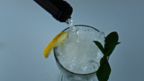 Bottle-pouring-liquid-cocktail-closeup.-Refreshing-iced-lemon-mint-beverage