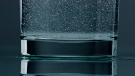 Closeup-fizzy-water-bubbling-in-glass.-Diverse-acid-bubbles-rising-liquid.
