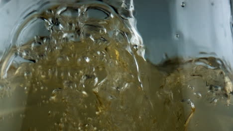 Bubbling-wine-pouring-glass-goblet-closeup.-Gold-sparkling-beverage-filling-cup