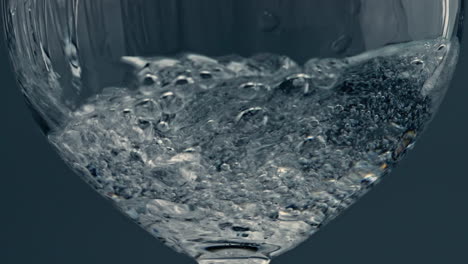 Nahaufnahme-Eines-Glases-Mit-Wasser-Auf-Dunklem-Hintergrund.-Spritzende-Flüssigkeit-Füllt-Tasse