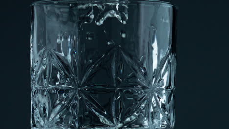 Nahaufnahme-Eines-Glases,-Das-Wasser-Auf-Dunklem-Hintergrund-Füllt.-Transparente-Tropfen-Fallen