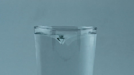 Pure-beverage-spinning-transparent-cylinder-closeup.-Filtered-aqua-rotating