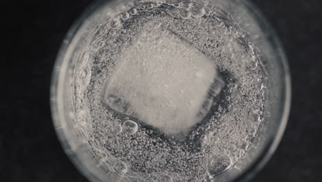 Closeup-ice-cube-glass-with-sparkling-water-in-slow-motion.-Cocktail-concept