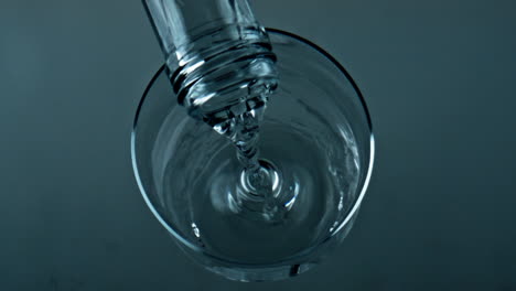 Botella-Vertiendo-Agua-Pura-En-Un-Vaso-Transparente-De-Primer-Plano.-Vista-Superior-De-Llenado-De-Líquido