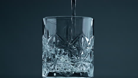 Wasser-Gießt-Kristallglas-Auf-Dunklem-Hintergrund,-Nahaufnahme.-Frische-Flüssigkeitsfüllung