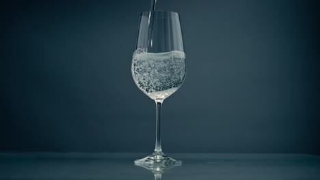 Sprudelndes-Wasser-Gießt-Glas-Auf-Grauem-Hintergrund,-Nahaufnahme.-Kristallklare-Flüssigkeit