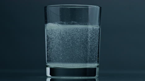 Air-bubbles-rising-glass-surface-closeup.-Acid-fluid-in-transparent-cup-at-dark
