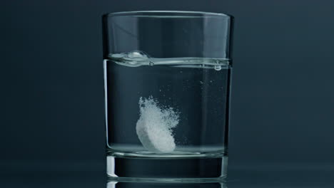Closeup-tablet-dropped-glass-at-dark-background.-Effervescent-pill-dissolving
