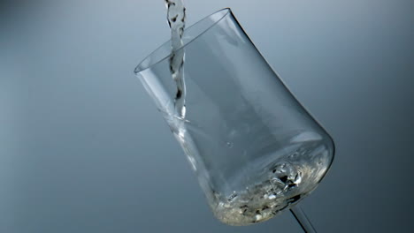 Wine-stream-pouring-glass-closeup.-Golden-grape-beverage-filling-beautiful-cup