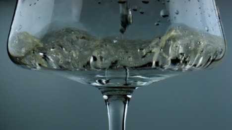 White-wine-filling-glass-closeup.-Sparkling-golden-alcohol-pouring-splashing-in