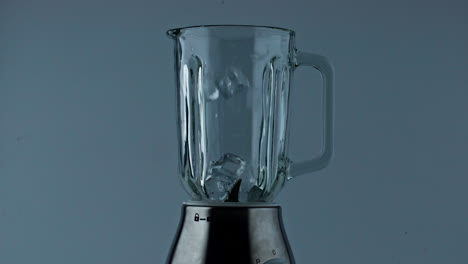 Ice-cubes-falling-mixer-bowl-close-up.-Cocktail-beverage-preparation-in-blender