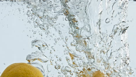 Yellow-citrus-falling-water-closeup.-Whole-lemons-splashing-bouncing-in-bubbling