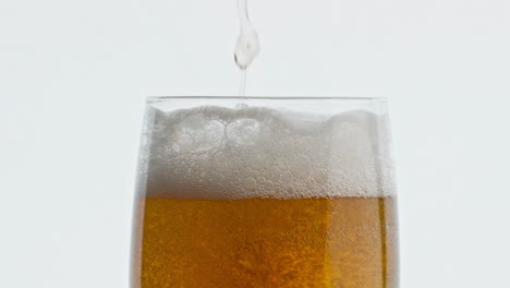 Pouring-hoppy-liquid-glass-closeup.-Unfiltered-barley-beer-stream-filling-goblet