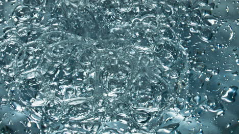 Small-air-bubbles-rising-up-to-water-surface-closeup.-Drink-filling-glassware