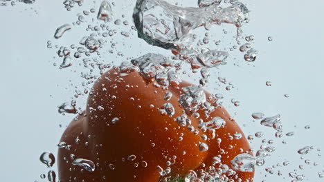 Closeup-sweet-pepper-falling-making-swirl-in-water.-Fresh-salad-ingredient-wash