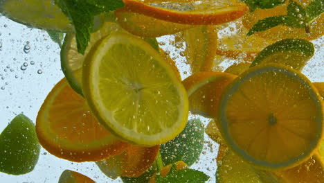Pieces-citrus-fruit-dropped-with-mint-in-water-closeup.-Sliced-orange-lemon-lime