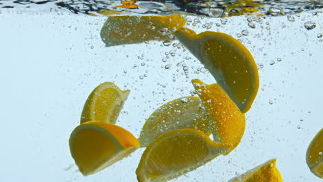 Dropping-orange-slices-liquid-close-up.-Citrus-wedges-raising-to-water-surface