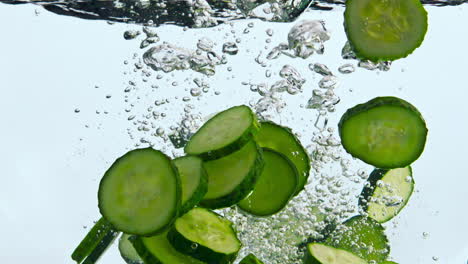 Closeup-pieces-cucumber-dropped-in-water.-Tasty-vegetable-falling-in-liquid.