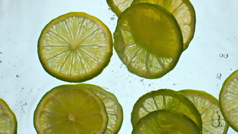 Closeup-sliced-lime-water-floating-in-super-slow-motion.-Citrus-dropped-liquid.