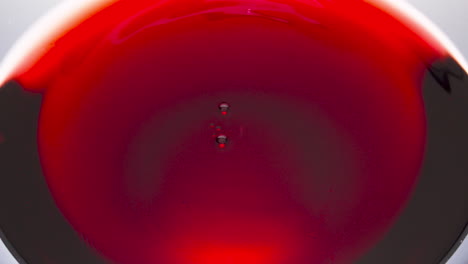 Rotweintropfen-Fallen-In-Super-Zeitlupen-Makro.-Nahaufnahme-Eines-Winkenden-Rosé-Schnapsglases