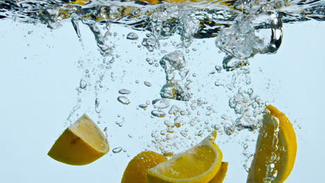 Orangenstücke-In-Wasser-Auf-Weißem-Hintergrund-Eingetaucht.-Zitrusschnitze-Spritzen-Flüssigkeit