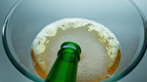 Bottle-pouring-craft-beer-in-transparent-glass-closeup.-Ipa-jet-making-bubbles