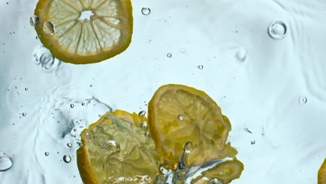 Zitrone-Fiel-Aus-Transparentem-Wasser,-Nahaufnahme.-Gelbe-Vitaminfrucht-Schwimmt-In-Flüssigkeit