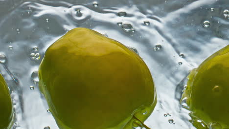 Organic-apples-floating-water-surface-closeup.-Tasty-green-fruits-washing-bounce