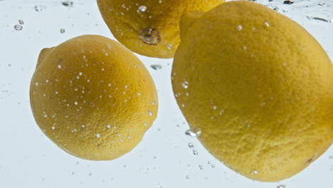 Lemons-flowing-bubbling-water-closeup.-Refreshing-summer-cocktail-preparation