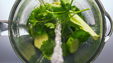 Liquid-pouring-vegetables-blender-super-slow-motion-closeup.-Top-view-mixer-bowl