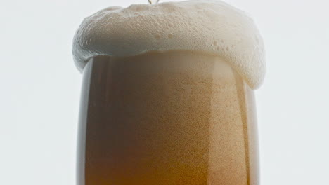 Ale-glass-foam-overflows-closeup.-Heady-mousse-pouring-over-the-vessel-edge