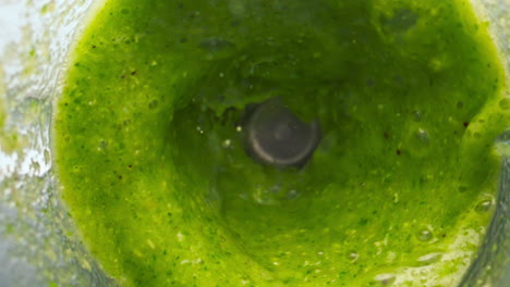 Green-vegetable-blend-mixing-in-blender-close-up-top-view.-Preparing-smoothie.