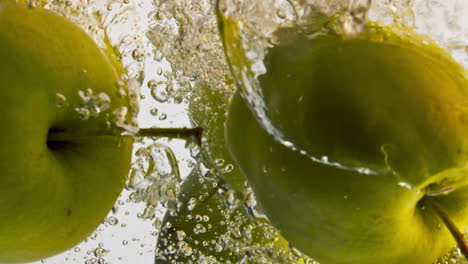 Whole-apples-falling-water-closeup.-Green-sour-fruits-flow-in-light-background.