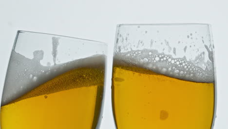 Cerveza-Burbujeante-Dos-Vasos-Tintineando-Fondo-Blanco.-Copas-De-Alcohol-Haciendo-Tostadas