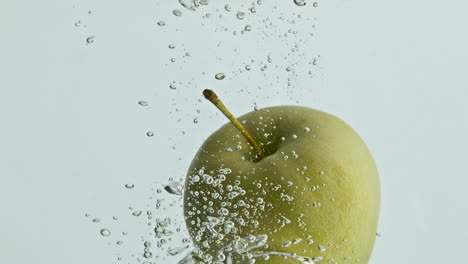 Fresh-apple-dropping-water-in-light-background-closeup.-Dynamic-tasty-fruit-fall