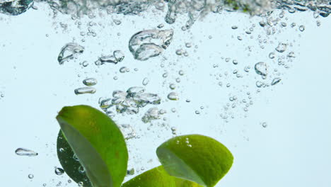 Lime-wedges-fall-water-in-super-slow-motion-close-up.-Citrus-splashing-liquid.