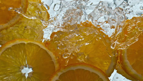 Orangenscheiben-Spritzen-In-Super-Zeitlupe,-Nahaufnahme,-Im-Wasser.-Schwimmende-Zitrusfrüchte.
