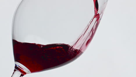 Wein-Füllt-Langsam-Das-Glas-Auf-Weißem,-Isoliertem-Hintergrund.-Alkoholisches,-Berauschendes-Getränk